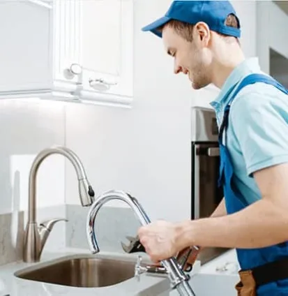 Technician replacing a kitchen faucet during plumbing or kitchen equipment service